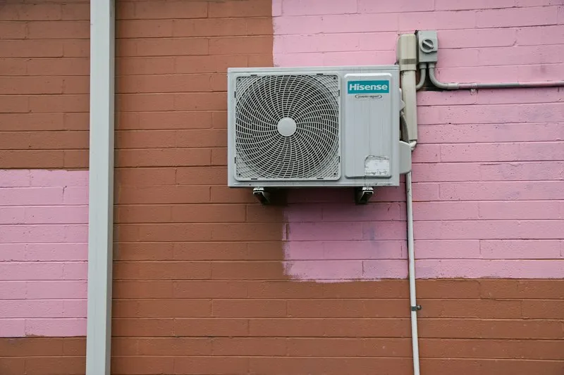 Air conditioning unit mounted on the painted brick wall of an apartment building