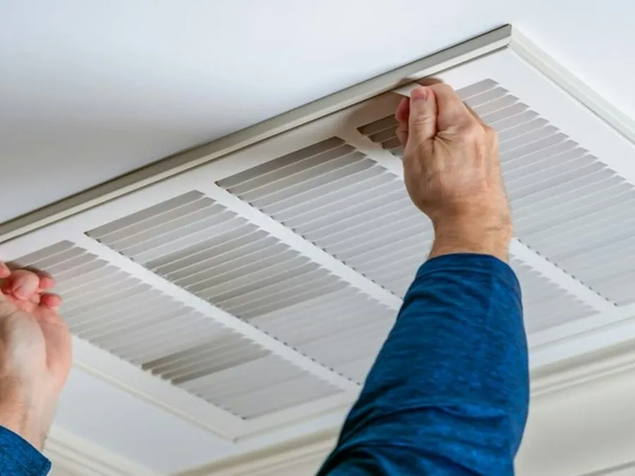 Technician servicing a ceiling-mounted office air conditioning unit