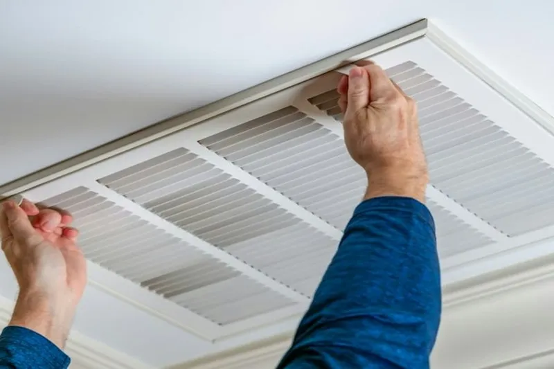 Technician servicing a ceiling-mounted office air conditioning unit